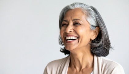Senior woman with gray hair laughing joyfully on a light background, exuding happiness and warmth in her expression