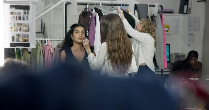 Woman, makeup artist and backstage with brush for application or prepare. Behind the scenes, cosmetics and model getting ready with stylist for foundation or fashion photoshoot in production studio