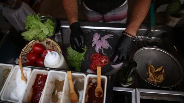 A cheff cutting vegetables to prepare a cheese burger