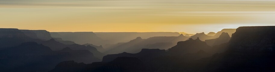 Panorama of the grand canyon arizona. Silhouettes of mountains on the horizon with the yellow sky at sunset.