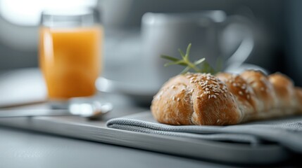 A freshly baked croissant served on a tray alongside a glass of orange juice creates a cozy and inviting breakfast scene, highlighting love for food and morning rituals.