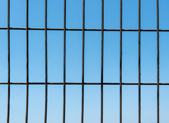 Metal grid pattern against a clear blue sky creates an industrial aesthetic in an urban environment during daytime