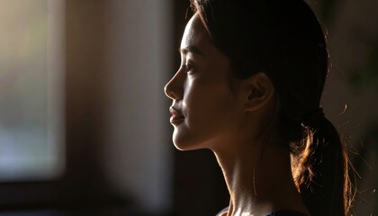 Profile portrait of a woman with gentle sunlight highlighting her features, captured in a tranquil indoor setting