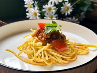 A serving of spaghetti adorned with a rich tomato-based sauce, garnished with fresh herbs. Presented on a white plate, it showcases the delicious combination of Italian-inspired flavors and textures.