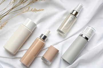 Assortment of neutral-toned cosmetic and skincare products neatly arranged with soft white roses in background.