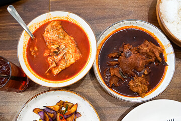 Top view of variety of dishes to be eaten with rice, namely asam pedas kepala ikan merah, ayam masak kicap and terung goreng lada.