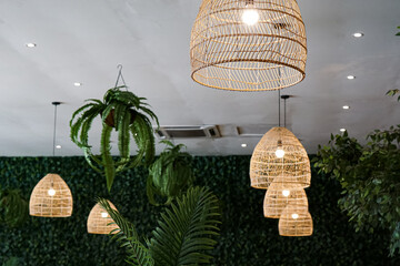 A beautifully designed interior with woven pendant lights and abundant greenery, providing a...