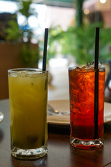 Iced drinks in tall glasses with straws on a restaurant table, with cozy dining ambiance.