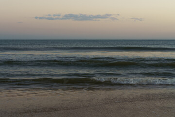 Smooth motion of waves reflecting the soft hues of sunset.