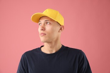 Young man in stylish baseball hat on pink background