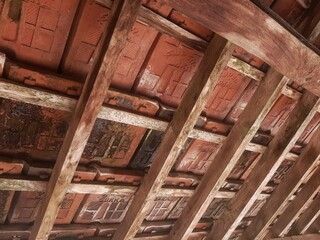 Traditional clay tile ceiling with wooden beams. Rustic, earthy tones. Architectural detail, natural building materials. Terracotta roof interior