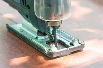 A carpenter cuts a board with an electric jigsaw