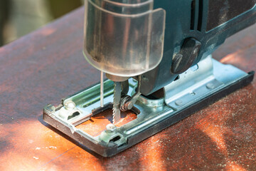 A carpenter cuts a board with an electric jigsaw