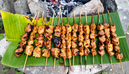 Traditional cuisine with grilled meat on skewers served on local banana leaf outdoors food meat grill bar-b-q skewer