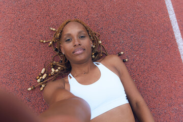 Sports woman takes a selfie for social media, lying on the running track, tired