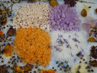 Obraz na płótnie Canvas Aromatic relaxing herbal and floral sea bath salt, various dried plants for making aromatic salt are on a blue background, top view