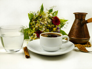 Coffee in a cezve and in a cup, a glass of water, cinnamon. Coffee and various additions to it.