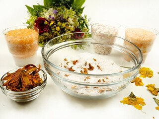 Dried red lily and calendula flowers added to sea salt in a glass bowl. Making aromatic relaxing...