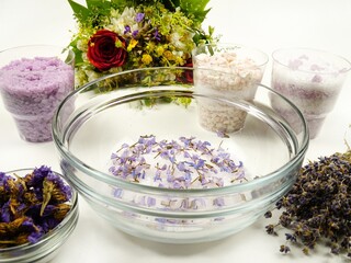Dried lavender flowers and sea salt in a glass bowl. Making aromatic relaxing herbal bath salt with...