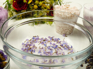 Dried lavender flowers and sea salt in a glass bowl. Making aromatic relaxing herbal bath salt with...