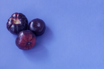 purple tomatoes on blue background top view