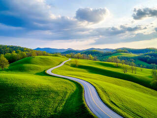 Naklejka premium A beautiful serpentine road winds through lush green hills in the heart of spring, inviting travelers to explore the vibrant landscape. Nature flourishes under the clear sky