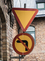 Road signs indicating yield and no left turn in a Swedish urban setting