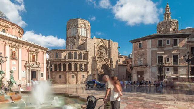 Panoramic timelapse hyperlapse of Valencia's Plaza de la Virgen, showcasing Turia Fountain, Cathedral and Basilica de la Virgen de los Desamparados in Spain's historic old town under a blue cloudy sky