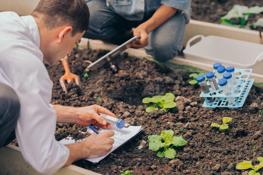 Multiracial students conducting farming and environmental research inside greenhouse laboratory.