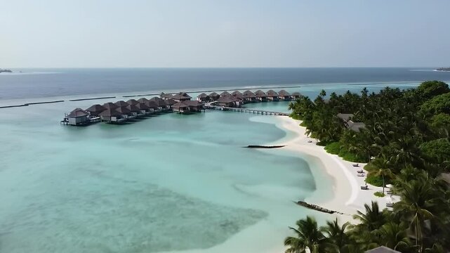 A cinematic aerial drone video flying over a stunning tropical island resort in the Maldives.