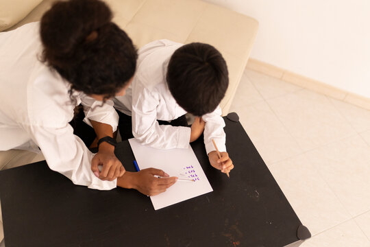 Mother helping son with homework, homeschooling on the table