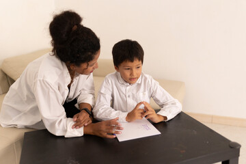 Teacher helping young boy with homework at home