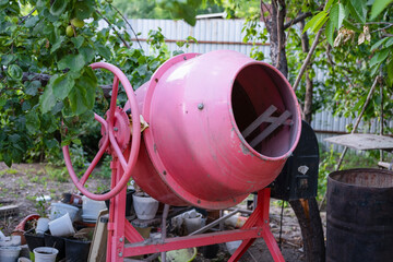 concrete is loaded into a cart from a 200 liter orange electric concrete mixer, photo taken on a...