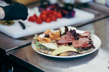 Plate with gourmet open-faced sandwiches topped with lettuce, cheese, prosciutto, and smoked...