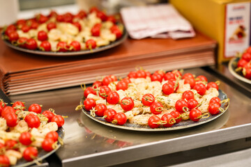 Appetizer platter with shrimp and cherry tomato skewers, neatly arranged for catering or buffet service. Fresh seafood finger food prepared in a professional kitchen.