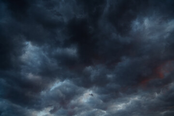 Black clouds with red edges, creeping over a calm sky landscape. Environmental issues, dramatic weather conditions