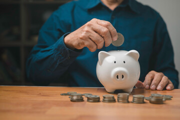 Savings concept, man hand is putting coins into piggy bank finance and investment, saving for...