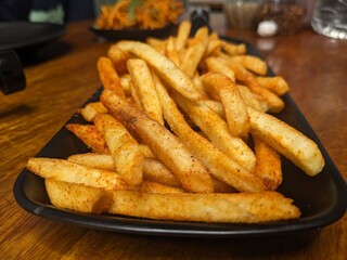 Freshly cooked French fries with spicy seasoning on a platter