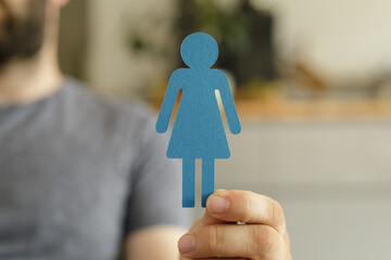 A man holds a blue paper cutout of a female figure. Concept for gender, equality, or identity.