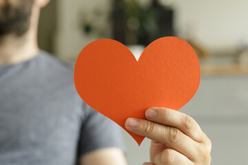 Close-up of a man's hand holding a bright red heart.  Perfect for love, romance, Valentine's Day.