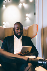 Modern African American businessman using tablet in office lobby