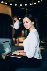 Smart businesswoman in formal wear browsing laptop at lobby of office center