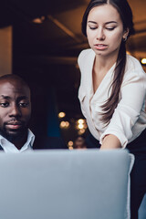 Multiethnic male and female executives using laptop at lobby of business center
