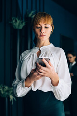 Serious manager watching smartphone at office space