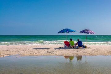 Couple of people with beach chairs and parasols on Siesta Beach in Siesta Key, Sarasota, Florida