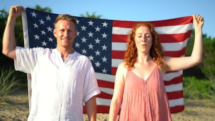 Two Friends Holding American Flag on the Beach. Patriotic Pride and Freedom by the Sea. Candid Video with USA Flag in a Scenic Location. - Powered by Adobe