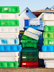 Colorful stacked crates in a Swedish harbour on a sunny day with boats in the background