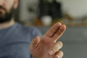 Close-up of a man's hand with fingers crossed, suggesting hope, luck, or a promise.