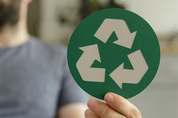 Image of a person holding a green recycling symbol. Perfect for eco-friendly campaigns.