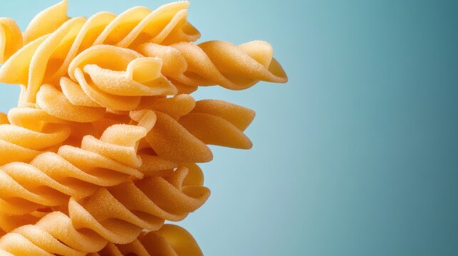 An artistic close-up of a vibrant twist pasta against a light blue background, showcasing its texture and design with an appealing and contemporary aesthetic.